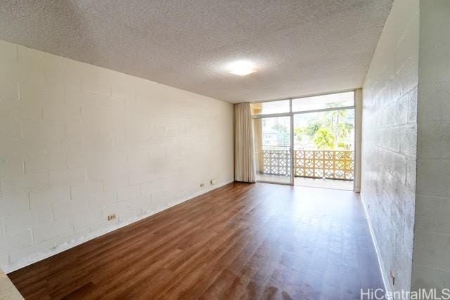 empty room featuring a wall of windows, hardwood / wood-style floors, and a textured ceiling