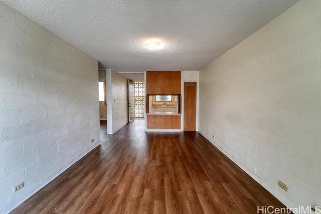 unfurnished living room with a textured ceiling and dark hardwood / wood-style flooring