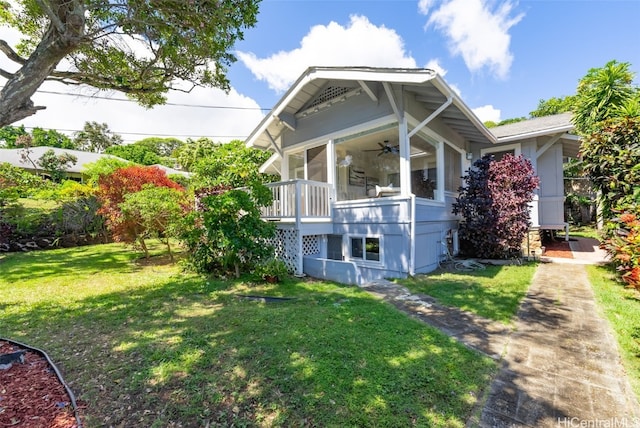 view of side of home featuring a lawn, a sunroom, and ceiling fan