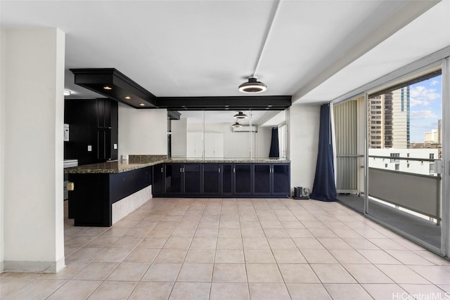 kitchen featuring light tile patterned flooring, kitchen peninsula, and dark stone countertops