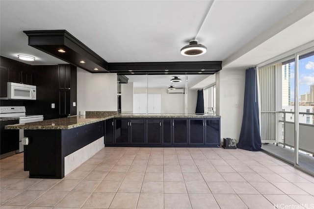 kitchen featuring dark stone countertops, white appliances, kitchen peninsula, and light tile patterned flooring