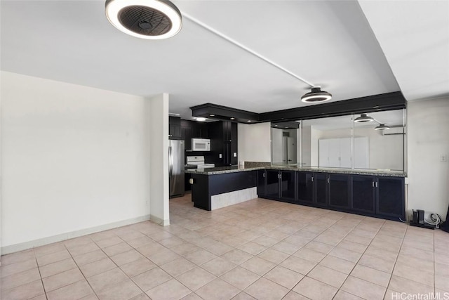 kitchen with light tile patterned floors, white appliances, light stone countertops, and kitchen peninsula