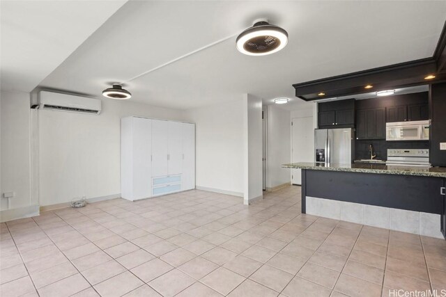 kitchen with electric stove, sink, stainless steel fridge, a wall mounted AC, and light stone countertops