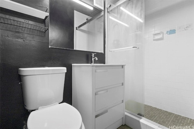 bathroom featuring toilet, vanity, and a shower with shower door