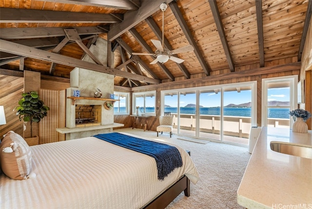 carpeted bedroom with a water view, access to exterior, wood ceiling, and a stone fireplace