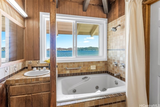 bathroom with sink, shower with separate bathtub, and a water view