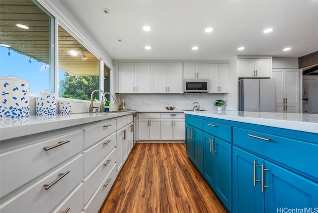 kitchen featuring stainless steel appliances, dark hardwood / wood-style floors, blue cabinets, and white cabinets