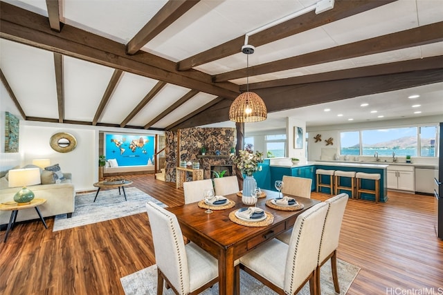 dining space with sink, a mountain view, lofted ceiling with beams, and light hardwood / wood-style flooring