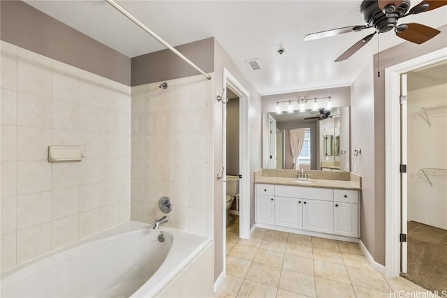 full bathroom with tiled shower / bath, vanity, ceiling fan, toilet, and tile patterned floors