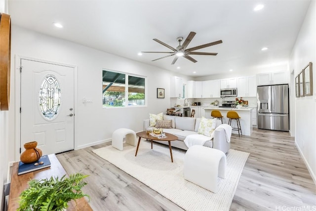 living room featuring sink, ceiling fan, and light wood-type flooring