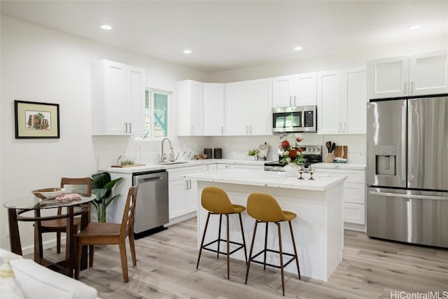 kitchen featuring a breakfast bar, sink, white cabinetry, a kitchen island, and stainless steel appliances