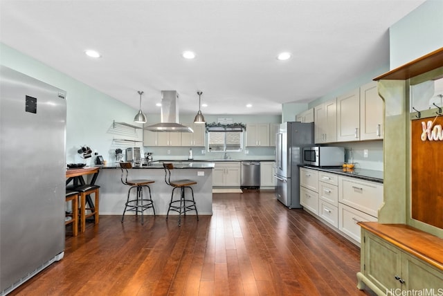 kitchen featuring a breakfast bar, hanging light fixtures, appliances with stainless steel finishes, dark hardwood / wood-style floors, and island exhaust hood