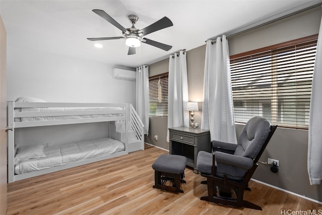 bedroom featuring an AC wall unit, ceiling fan, and light wood-type flooring