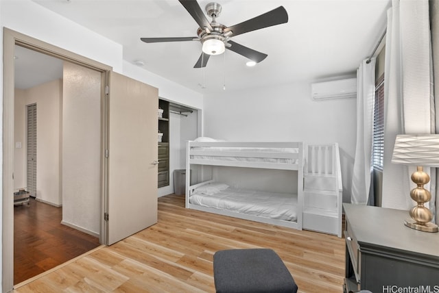 bedroom featuring wood-type flooring, a wall mounted AC, and ceiling fan