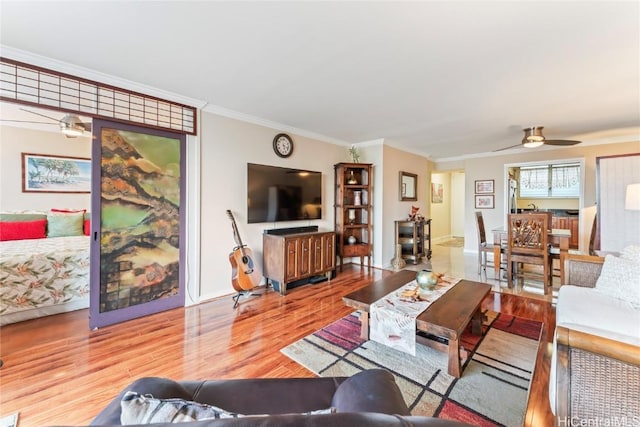 living room featuring wood-type flooring, ornamental molding, and ceiling fan