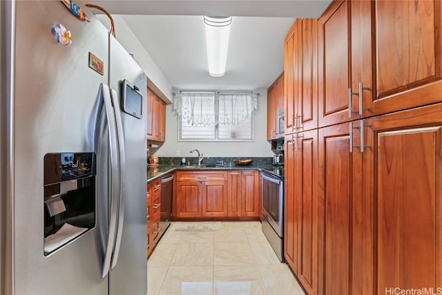 kitchen featuring stainless steel appliances, sink, dark stone countertops, and light tile patterned floors