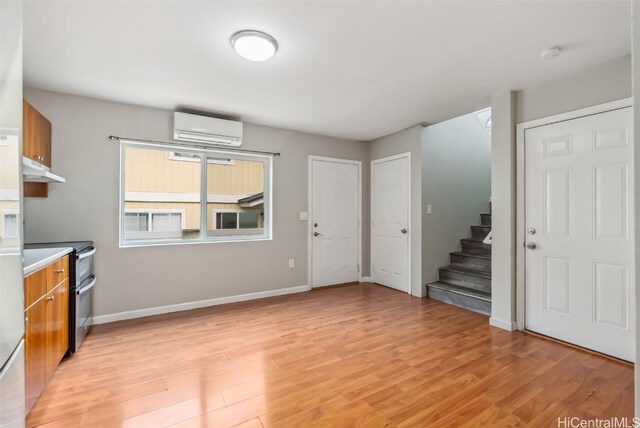 kitchen featuring light hardwood / wood-style floors, an AC wall unit, and range with two ovens