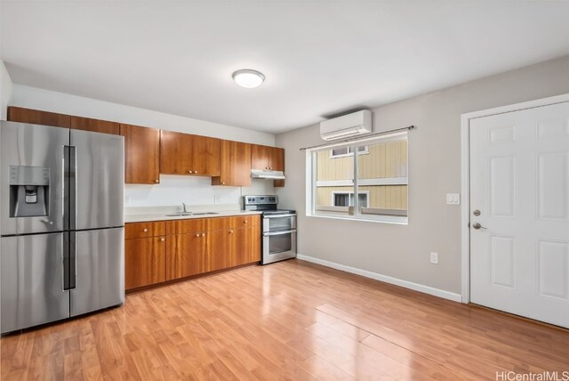 kitchen featuring stainless steel appliances, sink, a wall unit AC, and light hardwood / wood-style flooring