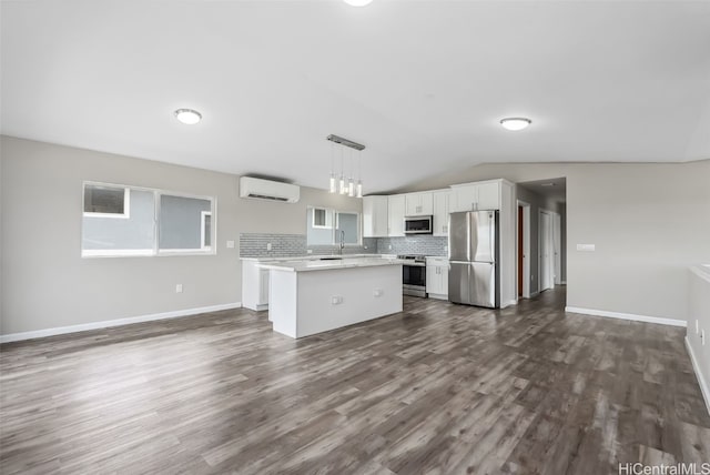 kitchen featuring white cabinetry, a wall mounted air conditioner, decorative light fixtures, appliances with stainless steel finishes, and a kitchen island