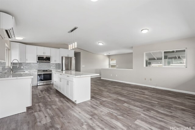 kitchen with sink, hanging light fixtures, stainless steel appliances, a center island, and white cabinets