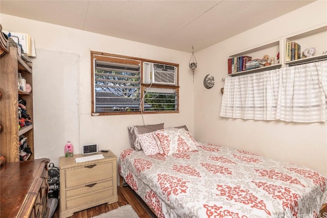 bedroom with a wall mounted air conditioner and dark wood-type flooring