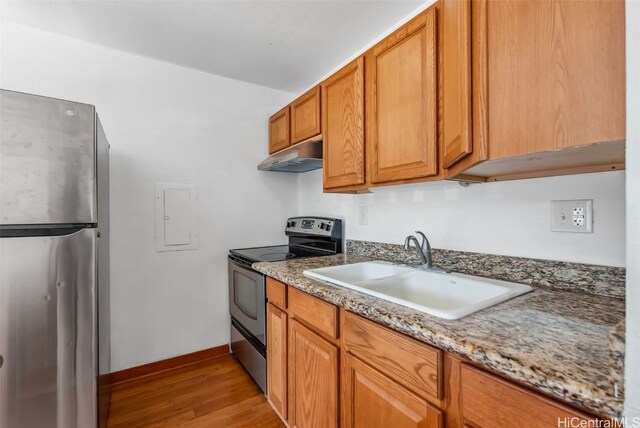 kitchen featuring sink, light wood-type flooring, appliances with stainless steel finishes, electric panel, and light stone countertops