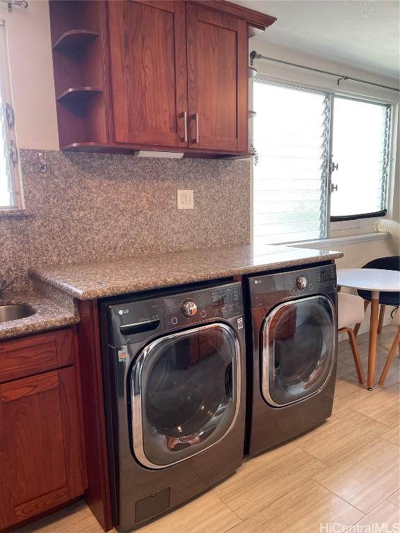 laundry room with cabinets, washer and dryer, and light hardwood / wood-style floors