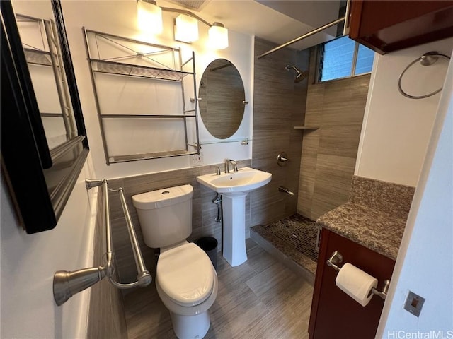 bathroom featuring tiled shower, sink, and toilet