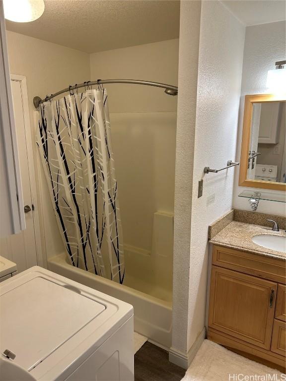 bathroom with vanity, washer / clothes dryer, a textured ceiling, and shower / tub combo with curtain