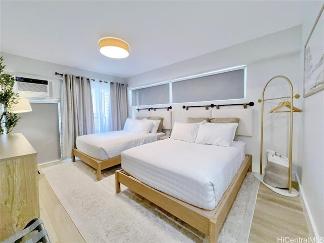 bedroom featuring a wall mounted air conditioner and light hardwood / wood-style flooring