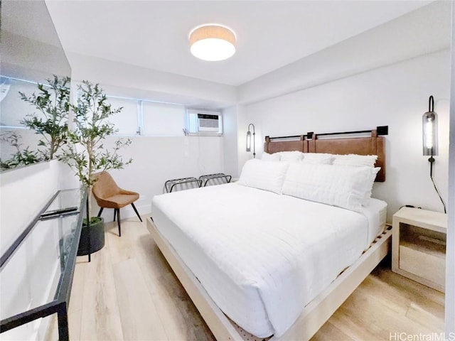 bedroom featuring a wall mounted AC and light hardwood / wood-style floors