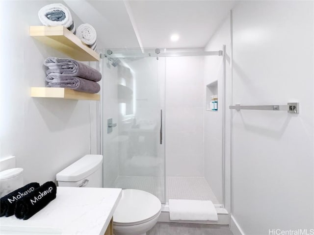 bathroom featuring vanity, a shower with door, and toilet