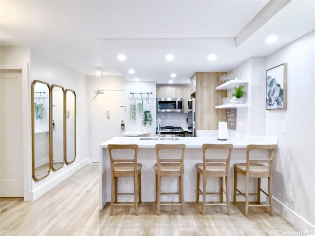 kitchen with appliances with stainless steel finishes, sink, a kitchen breakfast bar, and kitchen peninsula