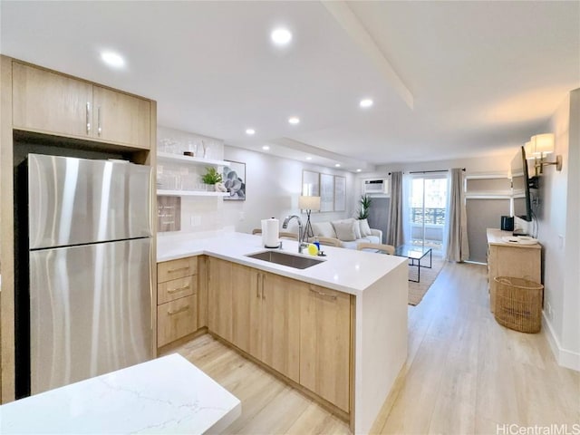 kitchen featuring sink, light brown cabinets, stainless steel refrigerator, kitchen peninsula, and light hardwood / wood-style floors