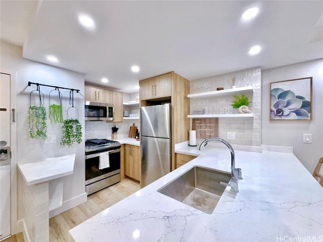 kitchen featuring sink, light hardwood / wood-style flooring, stainless steel appliances, light stone countertops, and light brown cabinets