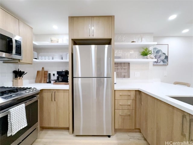 kitchen with tasteful backsplash, appliances with stainless steel finishes, light hardwood / wood-style flooring, and light brown cabinets