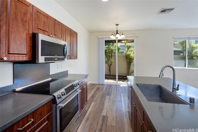 kitchen with pendant lighting, sink, stainless steel appliances, a notable chandelier, and light wood-type flooring