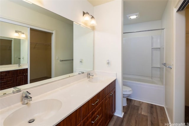 full bathroom with wood-type flooring, vanity, washtub / shower combination, and toilet