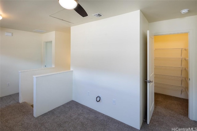 empty room with ceiling fan and dark colored carpet