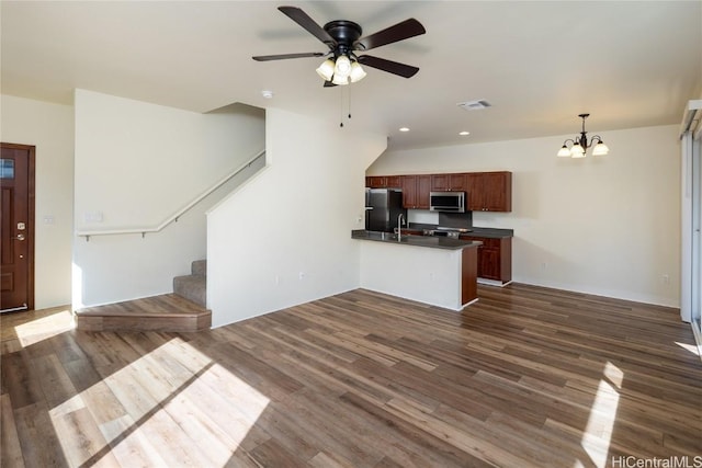 unfurnished living room featuring dark wood-type flooring and ceiling fan with notable chandelier