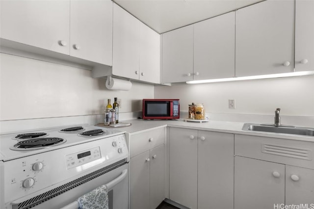 kitchen featuring white electric stove, sink, and white cabinets