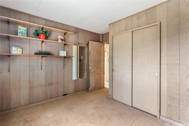 unfurnished bedroom featuring a closet and wood walls