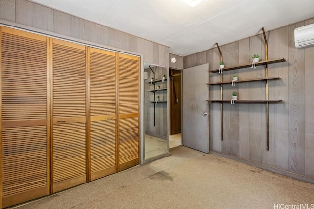 interior space with light colored carpet, wooden walls, a wall mounted AC, and a closet