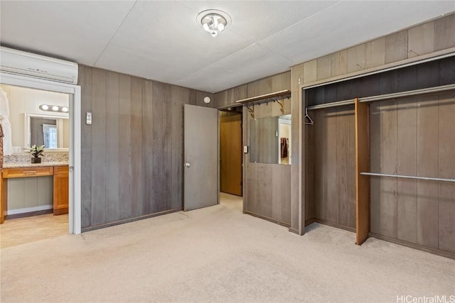 unfurnished bedroom featuring wooden walls, a wall mounted AC, ensuite bathroom, light carpet, and a closet