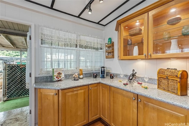 kitchen featuring rail lighting and light stone counters