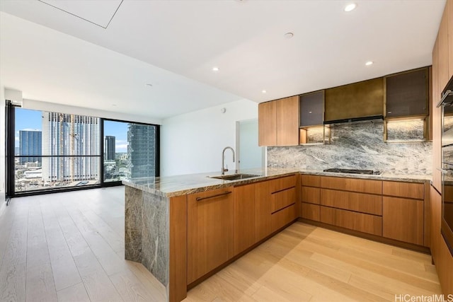 kitchen featuring sink, decorative backsplash, light hardwood / wood-style floors, and stainless steel gas cooktop