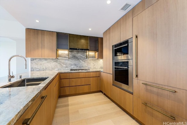 kitchen with light stone counters, sink, backsplash, and appliances with stainless steel finishes