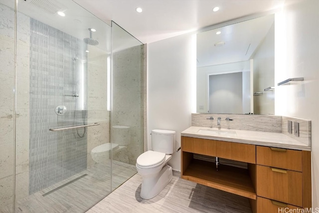 bathroom with an enclosed shower, vanity, tasteful backsplash, and toilet