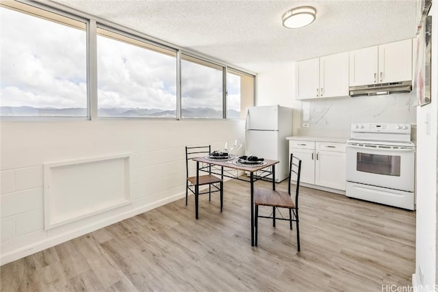 kitchen with white cabinetry, light wood-type flooring, a textured ceiling, and white appliances