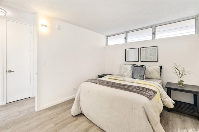 bedroom featuring light hardwood / wood-style flooring and a textured ceiling